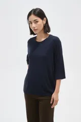 Remera de viscosa en color verde oliva, con cuello redondo y mangas 3/4. Presenta un diseño de tejido acanalado y corte holgado.