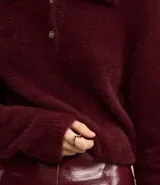 Saco de punto afelpado color bordó, de manga larga, con cuello polo y cierre frontal de dos botones.