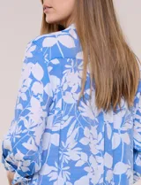 Blusa liviana de cuello mao con estampado floral en tonos azul y blanco, manga tres cuartos con presilla para arremangar, bolsillos frontales con solapa y cierre de botones nacarados.