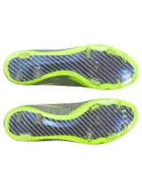 Championes de fútbol Under Armour Shadow Elite 3 FG, diseñados para velocidad y agilidad. Presentan una parte superior de tejido IntelliKnit gris con detalles en verde neón, logotipo de la marca en negro y suela exterior de fibra de carbono para máxima aceleración en superficies naturales.