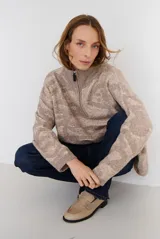 Buzo de tejido de punto con cierre frontal, cuello alto y diseño estampado en tonos beige y marrón.