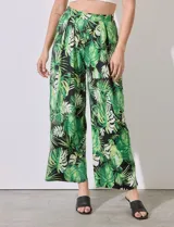 Pantalón largo de seda fría estampada con hojas de palmera en tonos verdes y blancos sobre fondo negro. Tiene pretina ancha elastizada.