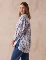 Blusa estampada con flores azules sobre fondo blanco, marca Floral & Ivy. Tiene cuello a la base con escote en V y aplique de botones. Las mangas son tres cuartos con puño y botón. Presenta tajos en las costuras laterales.