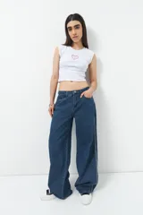 Pantalón de jean ancho color negro, de tiro bajo y confeccionado en algodón. Cuenta con una línea bordada color marrón en ambas piernas y cinco bolsillos.