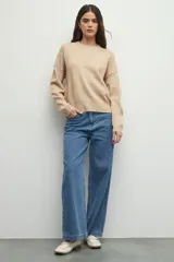 Sweater de tejido de punto color marrón, con cuello redondo y detalles de calados decorativos en el cuello y las mangas. Presenta un diseño de corte recto y manga larga.