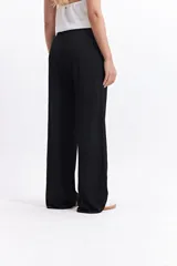 Pantalón de vestir de tiro alto, color crema, con textura crepe arrugada y pierna ancha y fluida. Presenta cintura elástica.