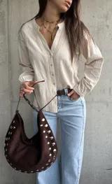 Camisa de manga larga color beige con diseño abotonado frontal, cuello mao y detalles de bordados y encaje en el frente y las mangas.