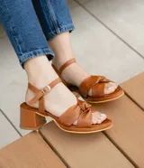 Sandalias de cuero color dorado, con plataforma y taco cuadrado. Presentan tiras cruzadas en el empeine y pulsera al tobillo con hebilla.
