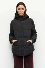 Campera puffer negra con capucha, diseño acolchado, cierre frontal con botones a presión, puños elastizados y bolsillos laterales.