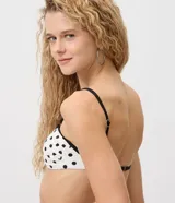 Top de bikini bandeau Bossa Nossa, confeccionado en microfibra con estampado de lunares negros sobre fondo blanco. Presenta breteles finos regulables y removibles de color negro, ribetes contrastantes en los bordes y frunces en los laterales.