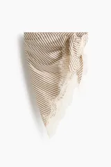 Pañuelo triangular de satén color beige con diseño a rayas diagonales marrones y delicado ribete de encaje blanco en los bordes.