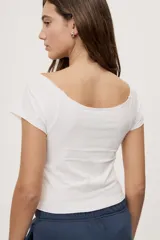 Remera blanca de corte ajustado y largo cropped, con escote redondo amplio y mangas cortas.