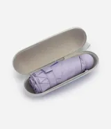 Sombrilla plegable color lila, de diseño compacto y estructura metálica con apertura manual y mango esférico a juego.