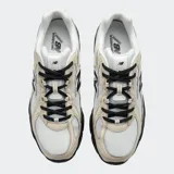 Championes urbanos New Balance modelo 740, con diseño inspirado en el running de los años 2000. Presenta una parte superior de malla técnica en color blanco con superposiciones sintéticas en tonos beige y detalles en negro. Incluye entresuela ABZORB para mayor amortiguación y suela de goma negra.