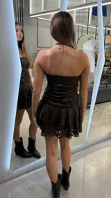 Vestido corto strapless de encaje color marrón oscuro, con diseño fruncido en el cuerpo y falda con volados en capas.