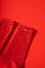 Medias de punto acanalado en color rojo intenso, con puño elástico. Presentan un detalle de corazón bordado con la letra R en la parte superior y el logo de la marca en la planta del pie.