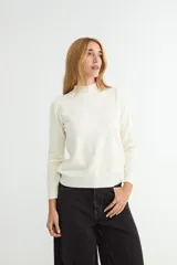 Polera de punto color beige, con cuello alto y mangas largas, de diseño básico y ajuste clásico.