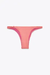 Braguita de bikini de tiro medio, con textura gofrada en tonos coral y naranja, y forro interior fucsia. Presenta un nudo decorativo en el lateral izquierdo.
