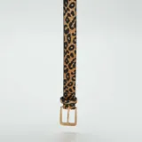 Cinturón fino con estampado de leopardo, hebilla metálica dorada y reverso de cuero negro.