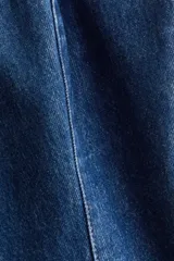 Chaleco sastrero en denim de algodón rígido, con escote recto, breteles finos y cierre frontal de botones metálicos. Presenta costuras princesa al frente y una abertura pronunciada en el dobladillo inferior.