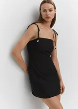 Vestido corto negro de lino con tirantes finos ajustables con lazada y detalle de abalorios.