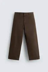 Pantalón de algodón color marrón oscuro, estilo balloon fit, con talle alto, cierre frontal y trabillas ajustables en los bajos. Presenta costuras verticales marcadas en el frente de cada pierna.