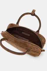 Bolso mini bowling color marrón de cuero gamuza, con doble asa de mano y correa bandolera extraíble. Tiene cierre de cremallera y bolsillo interior con cremallera.