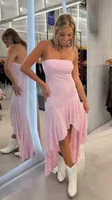 Vestido largo rosado con brillo, strapless y diseño asimétrico con volados en la parte inferior.