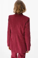 Blazer de corte clásico confeccionado en tela aterciopelada color bordó, con cuello solapa, cierre frontal con botones y bolsillos laterales tipo ojal.