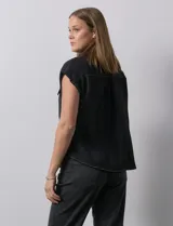 Blusa negra con cuello con solapa y escote en V, con bolsillos delanteros y pespuntes blancos.