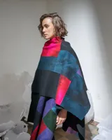 Ruana confeccionada en lana merino afieltrada, con diseño geométrico multicolor inspirado en los cultivos del campo.
