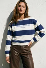 Sweater de algodón a rayas horizontales en color blanco y azul marino, con cuello redondo, manga larga y el texto bordado "The Creative Club URUGUAY" en el frente.
