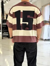 Remera de punto a rayas horizontales en tonos azul marino y beige, de manga corta y corte oversize. Presenta un gran número 15 rojo estampado en la espalda.