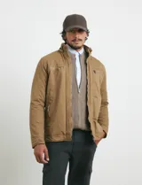 Campera de tejido técnico elástico en color verde oliva, con capucha integrada, cierre frontal y bolsillos con cierre en el pecho. Cuenta con forro interior de micro polar y diseño funcional.