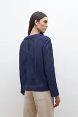 Sweater de punto calado en color azul, con cuello polo y escote en V. Presenta mangas largas con puños rectos y un diseño de tejido vertical.