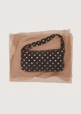 Bolso de hombro tipo baguette confeccionado en piel bovina color marrón oscuro, con diseño estructurado y superficie decorada con tachas metálicas plateadas distribuidas uniformemente. Cuenta con cierre superior y asa integrada.
