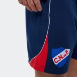 Short deportivo Umbro del Club Nacional de Football, color azul marino con detalles en rojo y blanco, escudo del club en la pierna derecha y logo de la marca en la izquierda.
