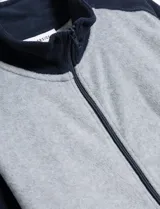 Campera gris jaspeado con cuello alto, cierre frontal y detalles en azul marino en hombros, cuello y puños.