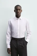 Camisa de corte regular fit con cuello italiano y manga larga con puños abotonados. Presenta un diseño de rayas verticales finas en tono suave sobre fondo claro, con cierre frontal de botones.