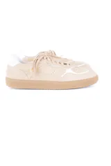 Championes de estilo deportivo vintage, confeccionados en una combinación de cuero vacuno y gamuza en tonos beige. Presentan un diseño de líneas curvas con detalles en blanco, cordones al tono y suela plana de goma en color tostado.