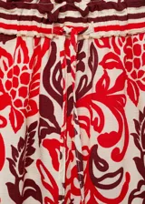 Pantalón largo de corte recto y tejido fluido, con estampado paisley en tonos rojo, bordó y crudo. Cuenta con cintura elástica con cordón ajustable y bolsillos laterales.