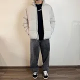 Campera puffer color gris claro, con cuello alto y cierre frontal con cremallera.