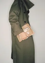 Abrigo tipo trench de diseño oversize y corte recto, color verde militar. Presenta cuello de solapa ancha, cierre frontal de doble botonadura, cinturón desmontable con hebilla y bolsillos laterales. Incluye trabillas en los puños y forro interior.