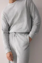 Conjunto de pijama de dos piezas en punto waffle gris claro, compuesto por una remera de manga larga con cuello redondo y un pantalón con cintura elástica y cordón de ajuste.
