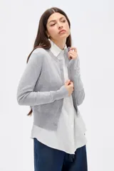 Saco de punto al cuerpo, color negro, con cuello redondo, manga larga y cierre frontal con botones pequeños.