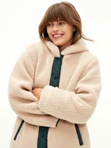 Campera acolchada de color verde oscuro con diseño matelasseado, interior forrado en corderito sintético color beige, con capucha y cierre frontal de botones a presión.