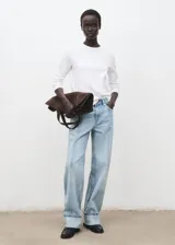 Jeans tiro medio color celeste, de diseño recto y largo, con bajo vuelto, trabillas, cierre de botón y cremallera, estilo cinco bolsillos y detalle de costuras verticales.