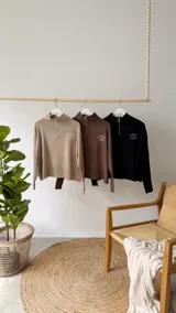 Sweater de tejido bremer color blanco, con cuello polo, cierre frontal y bordado en el pecho. Presenta mangas largas y diseño de corte holgado con terminaciones acanaladas.