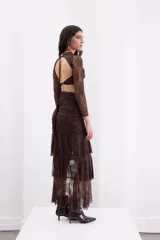 Falda larga de encaje color negro, de silueta ajustada con volados escalonados y abertura lateral pronunciada.