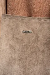 Bolso tipo tote de gran tamaño en color camel, confeccionado en cuero vegano con acabado efecto gamuza. Presenta doble asa larga para llevar al hombro y una placa metálica pequeña con el logo de la marca en el frente.